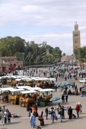 Image du Maroc Professionnelle de  Les calèches de jus d'orange sont bien alignés sur La mythique place Jemaa El Fana, avec ses charmeurs de serpents, lieu incontournable de Marrakech, la ville touristique du Maroc, Dimanche 27 Février 2005, au fond le minaret de la Koutoubia. (Photo / Abdeljalil Bounhar)